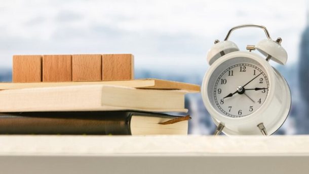 alarm clock ,cubes and books on wooden table